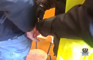 Na zdjęciu policjant zakłada kajdanki zatrzymanemu mężczyźnie.
