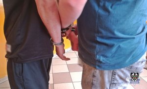 Na zdjęciu policjant zakłada kajdanki drugiemu z zatrzymanych mężczyzn.